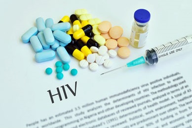 A document titled "HIV" covered with tablets of various colors and shapes, a vial of fluid and a hypodermic syringe
